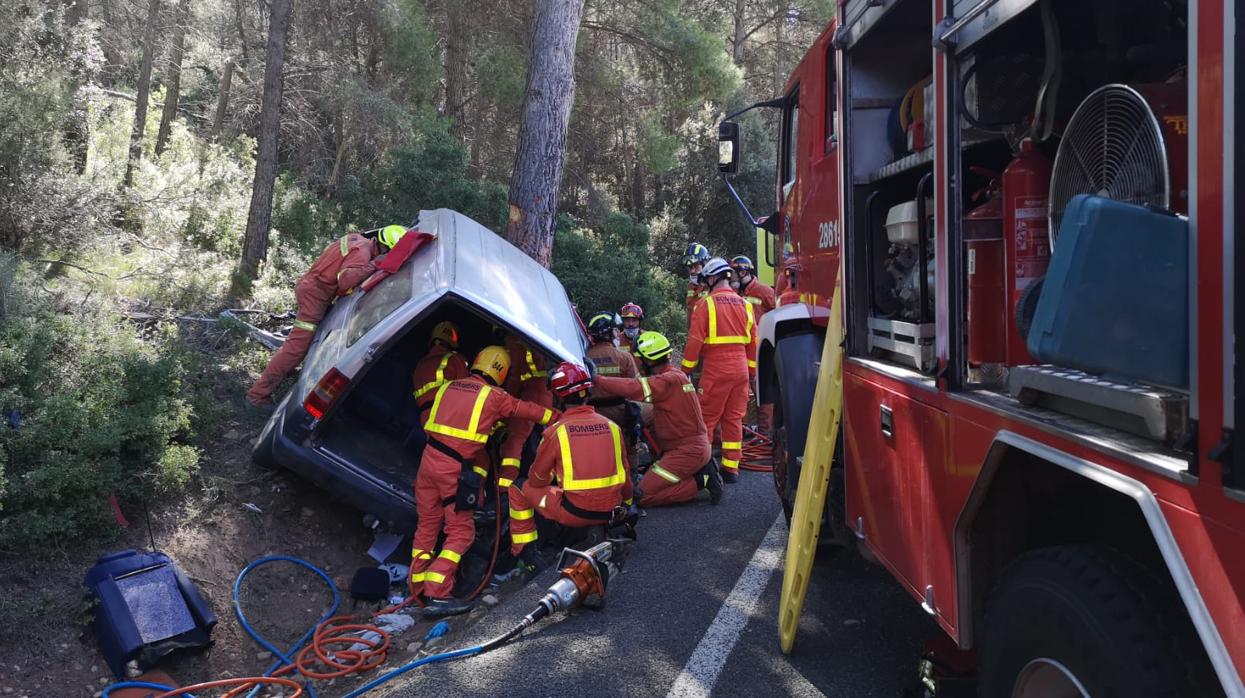 Efectivos de Bomberos rescatando a los dos ocupantes del vehículo, atrapados tras chocar con el árbol