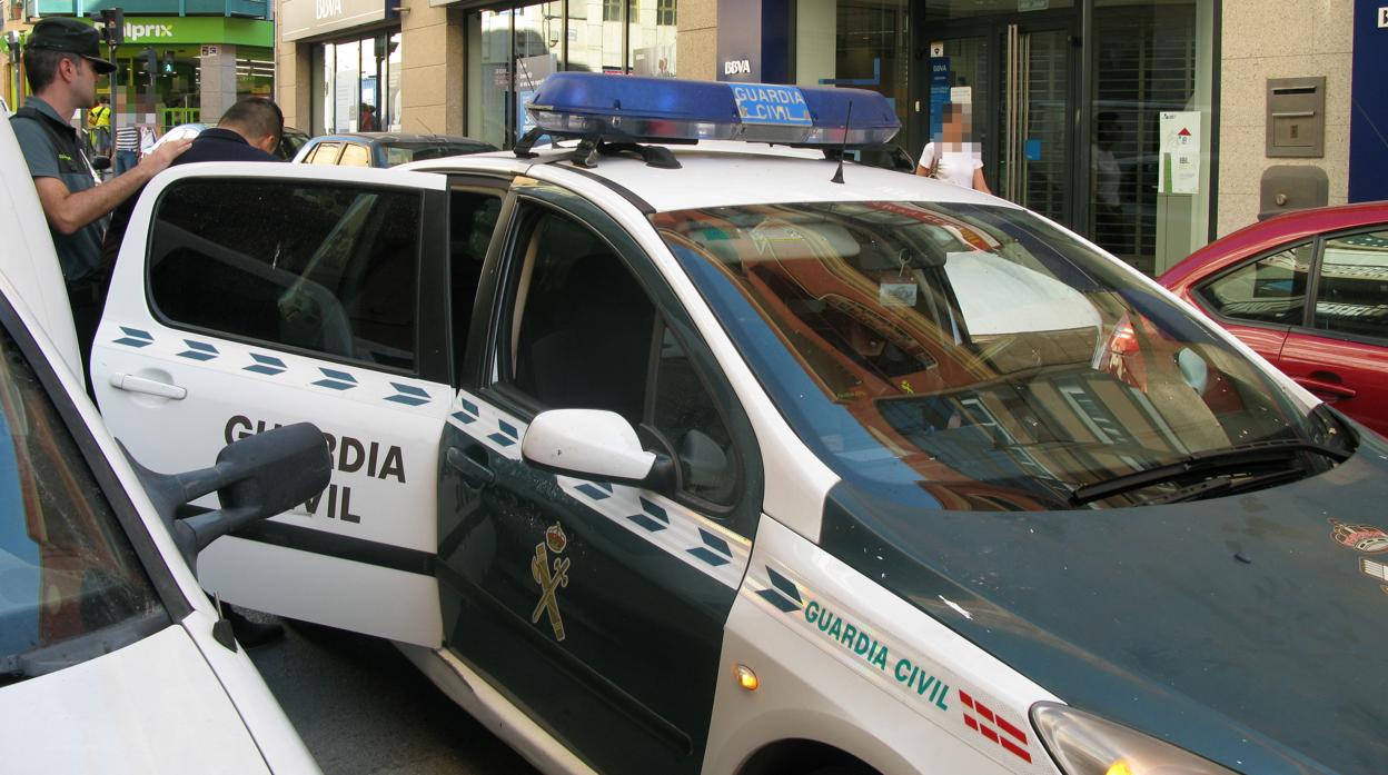 El detenido, custodiado por la Guardia Civil junto a la entidad bancaria donde ha sido identificado