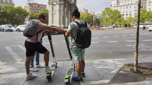 Dos usuarios de patinetes eléctricos arrancan un vehículo en la Puerta de Alcalá