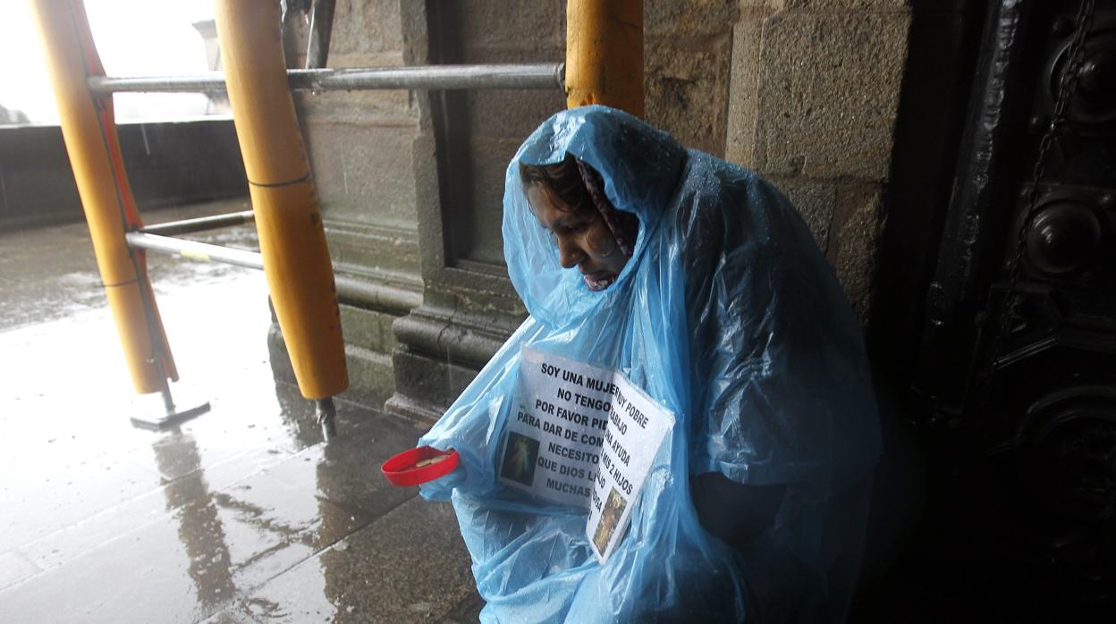 Una mujer mendiga bajo la lluvia en las afueras de la Catedral compostelana