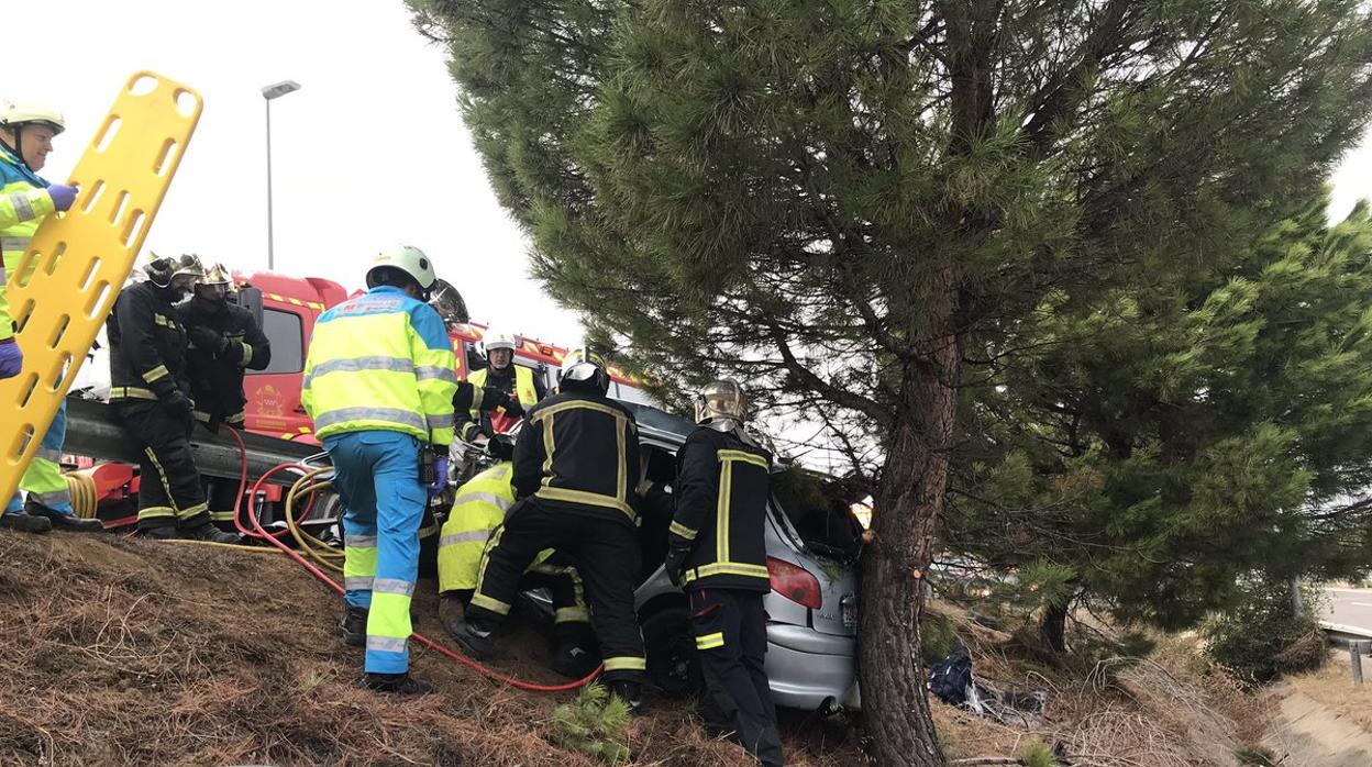 Los bomberos tratan de rescatar al joven en el interior de su vehículo