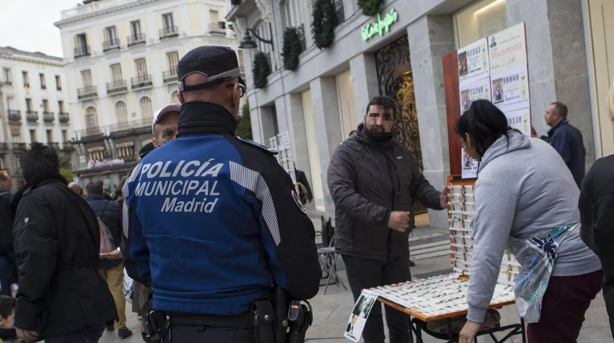 Un Policía Municipal habla con dos loteros ambulantes en Sol