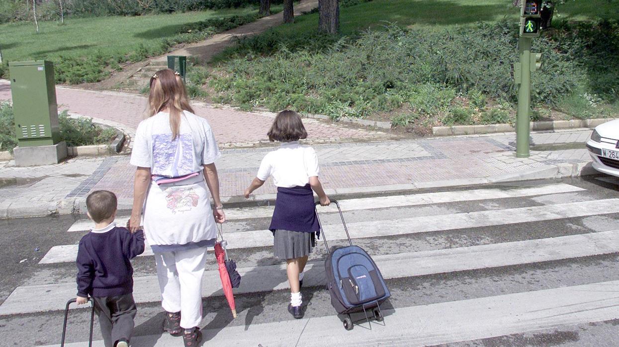 Dos alumnos vestidos con uniforme escolar circulan por un paso de cebra