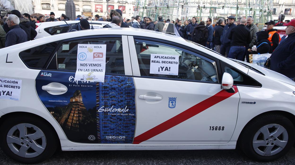 Uno de los taxis aparcados en Sol, con un cartel que pide la aplicación del Real Decreto