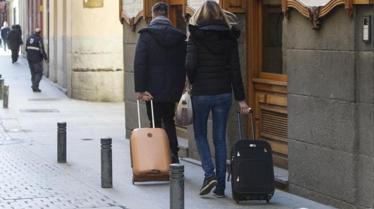 Dos turistas pasean con sus maletas por el barrio de Las Letras