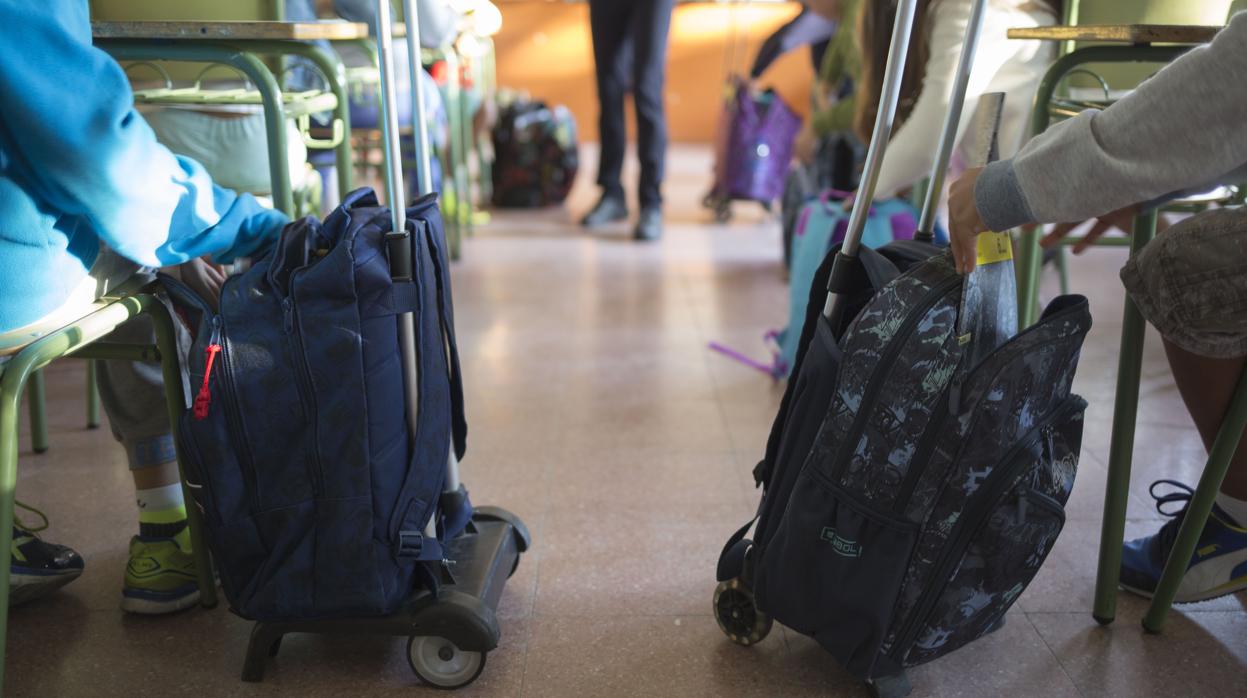 Dos escolares con sus mochilas cargadas de libros de texto