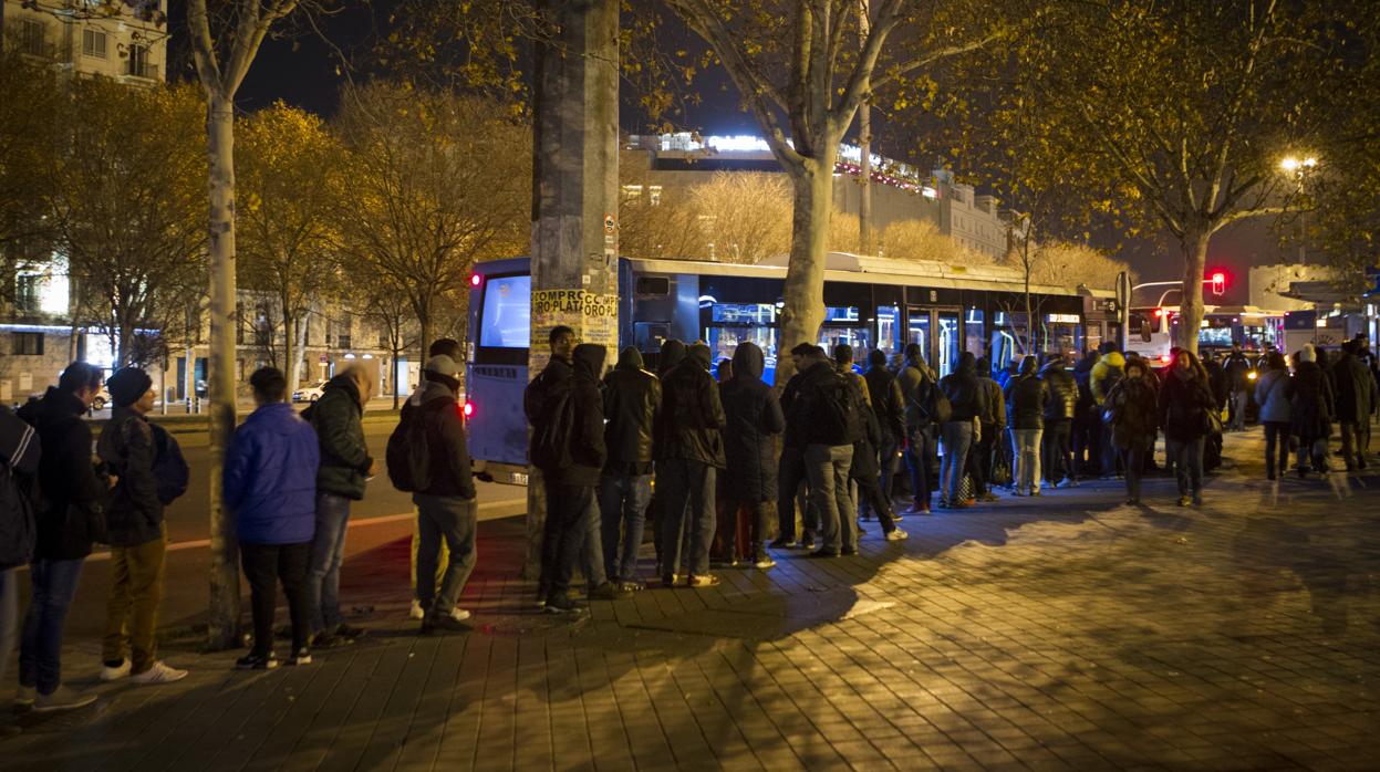 Decenas de sintecho esperan en Atocha el autobús que los transporta al albergue de Vallecas