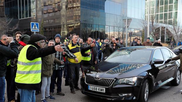 Un grupo de taxistas ante un vehículo con licencia VTC a las puertas del recinto ferial de IFEMA, donde se celebra la feria de turismo, FITUR