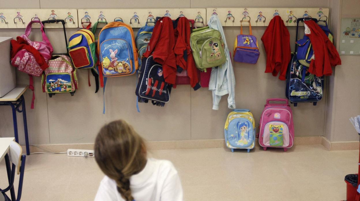 Una niña observa las mochilas en una clase