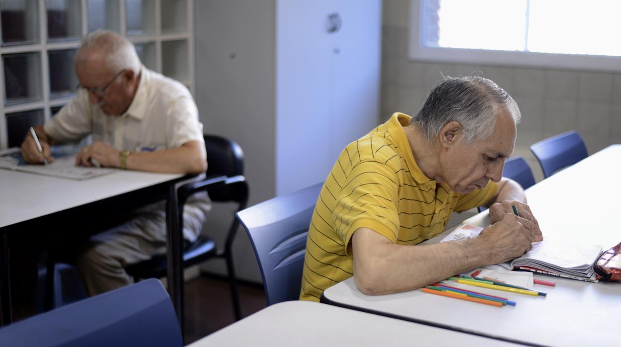 Usuarios de un centro de día leyendo y haciendo ejercicios