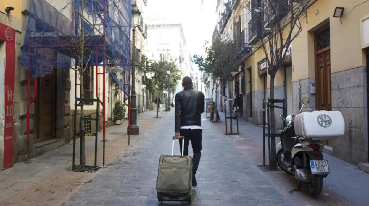 Un turista recorre las calles del barrio de Las Letras con su maleta