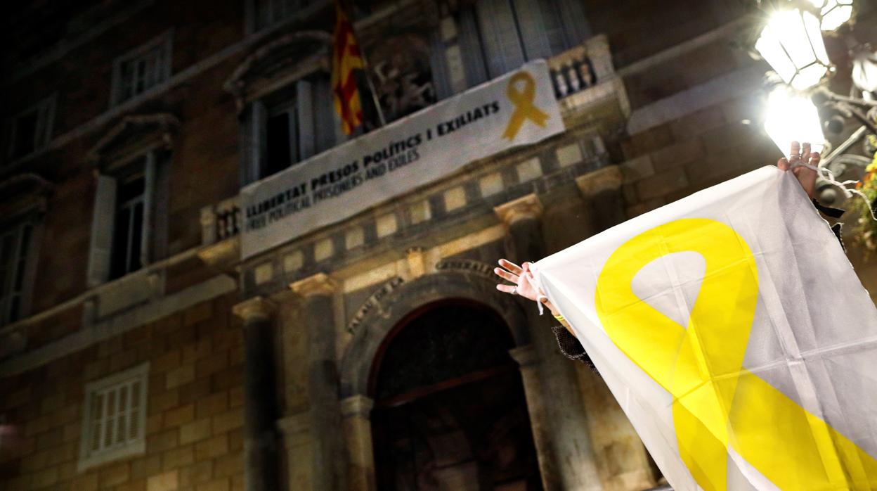 Una mujer muestra una pancarta con una lazo amarillo ante el Palau de la Generalitat