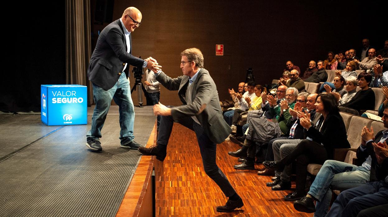 El presidente del PP de Orense, Manuel Baltar, ayuda a Feijóo a subir al escenario en Celanova