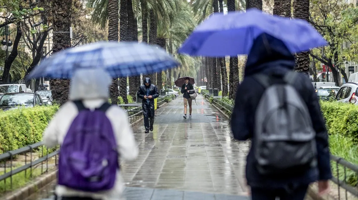 Unos jóvenes se protegen de la lluvia en Valencia