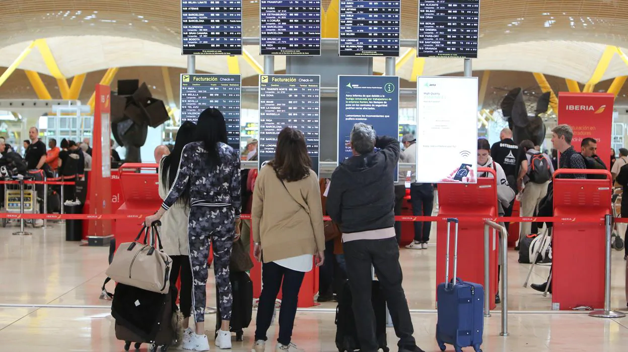 Cuatro turistas observan las pantallas de información del aeropuerto