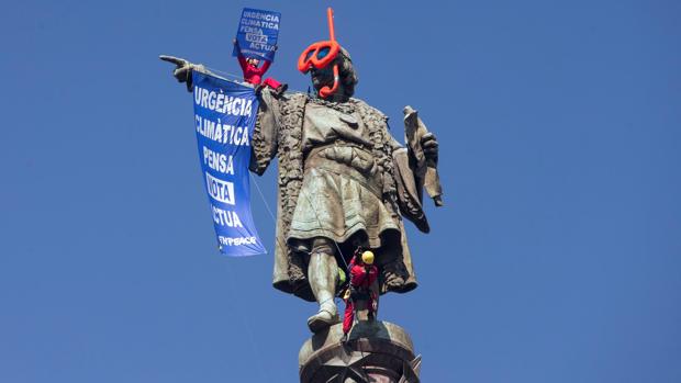 Dos activistas de Greenpeace colocan unas gafas de buzo a la estatua de Colón en Barcelona