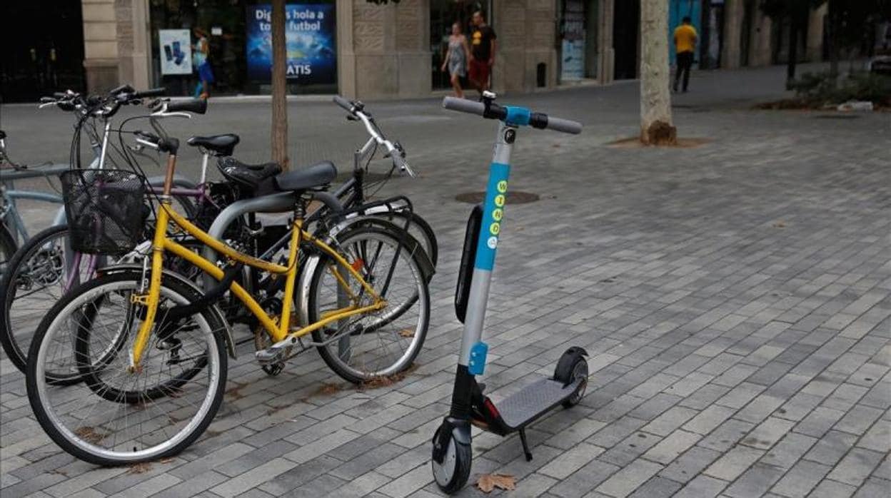 Un patinete eléctrico aparcado junto a unas bicicletas