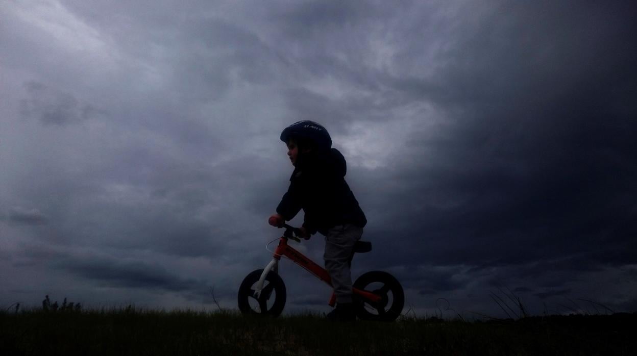 Un pequeño juega con su bici, en mitad de la borrasca