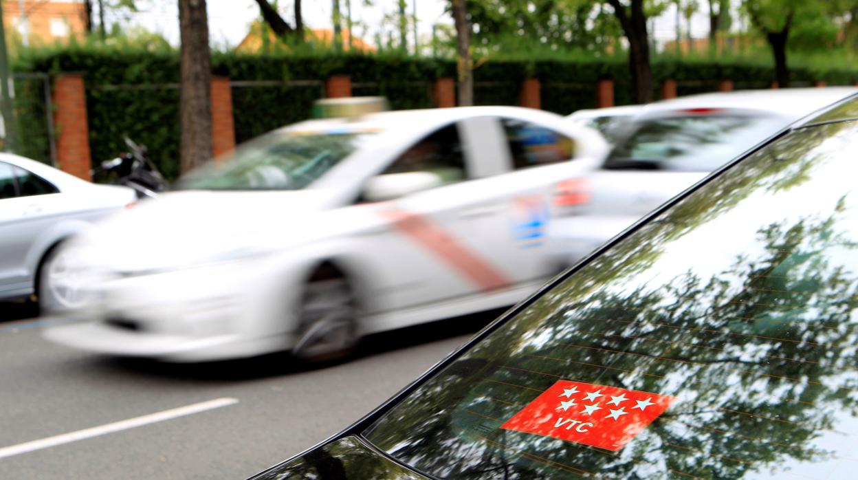 Un coche VTC y un taxi, en la ciudad de Madrid