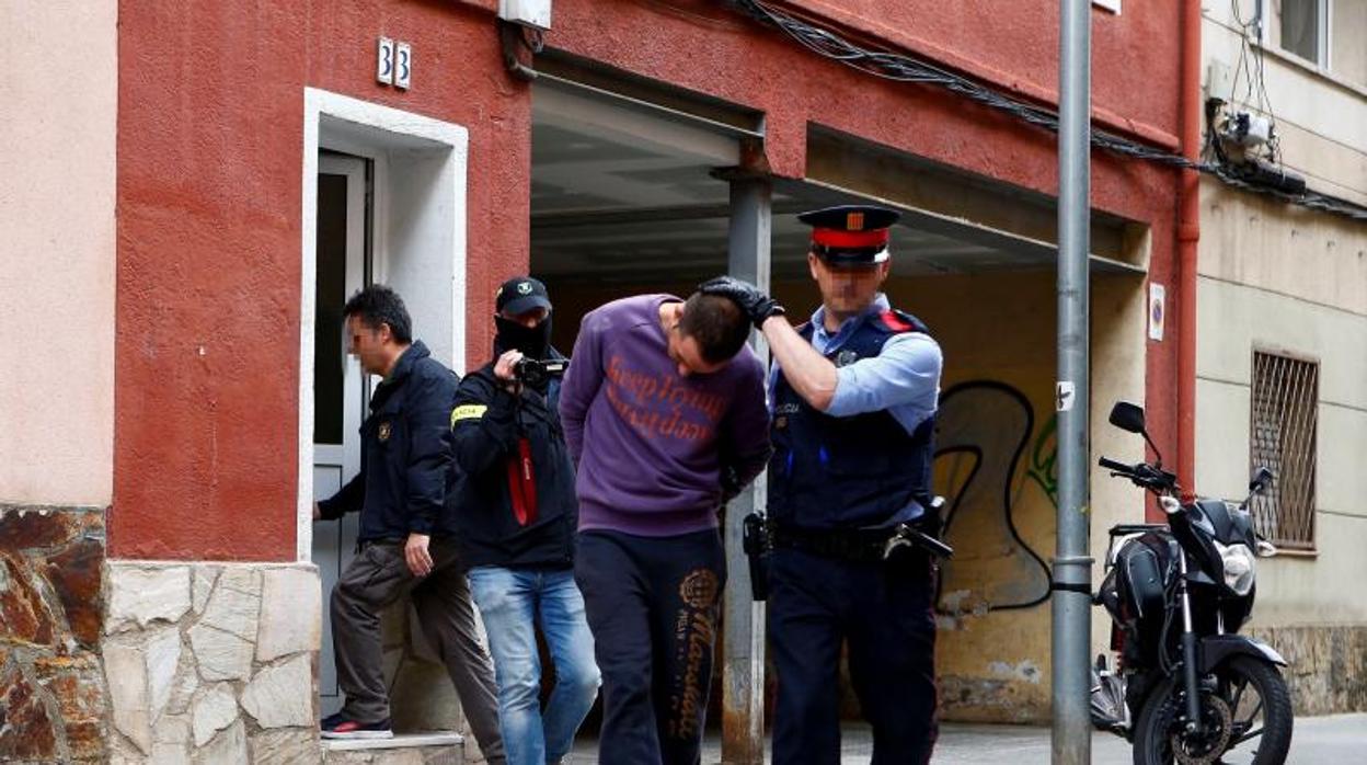 Los Mossos conducen al detenido tras el registro de su vivienda en Cornellá