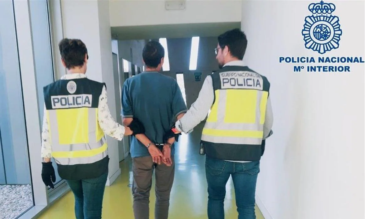Dos agentes de la Policía Nacional llevan esposado al detenido