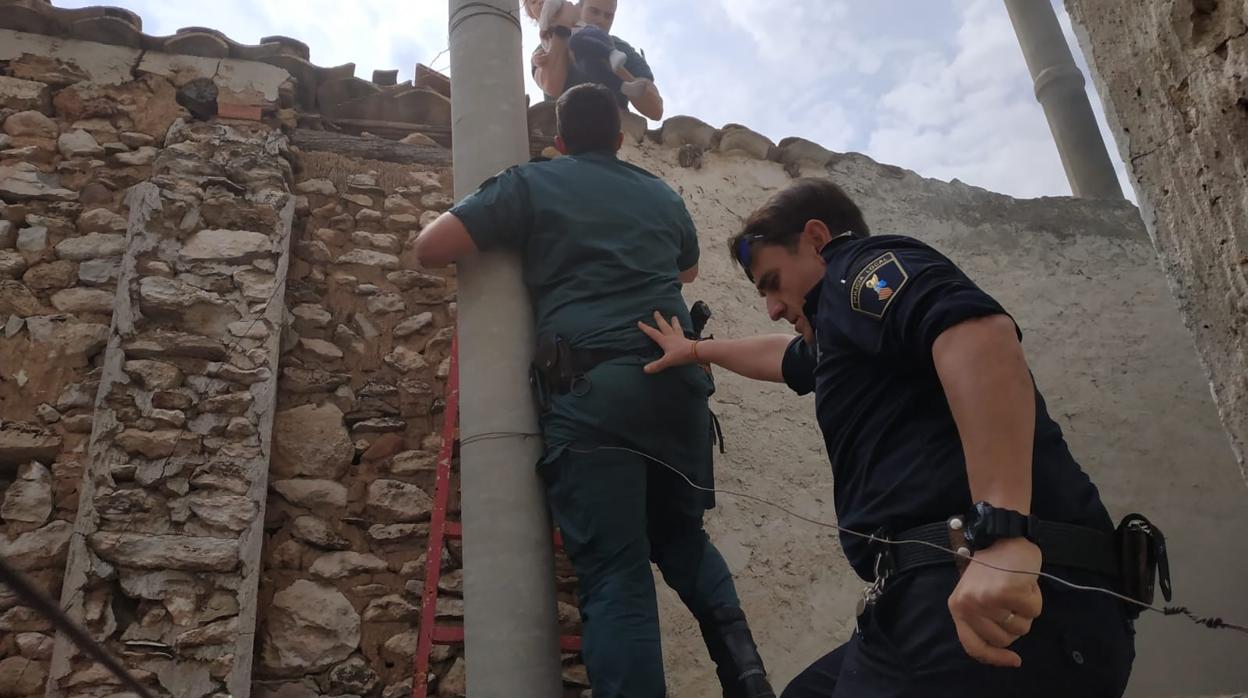 Dos guardias civiles y un policía local en el momento de sacar al bebé de la vivienda incendiada