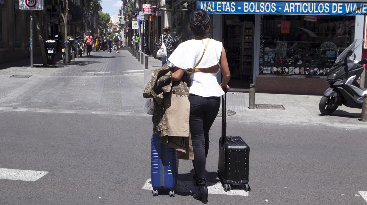 Una mujer camina con dos maletas, por el centro de la capital