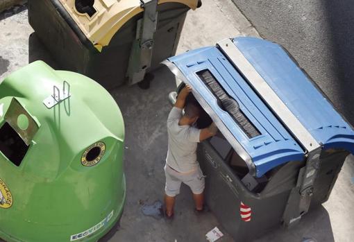 Un joven revisa el contendo de los contenedores en Valencia