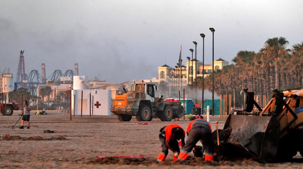 Los servicios de limpieza trabajan en la mañana de este lunes en las playas valencianas tras la noche de San Juan