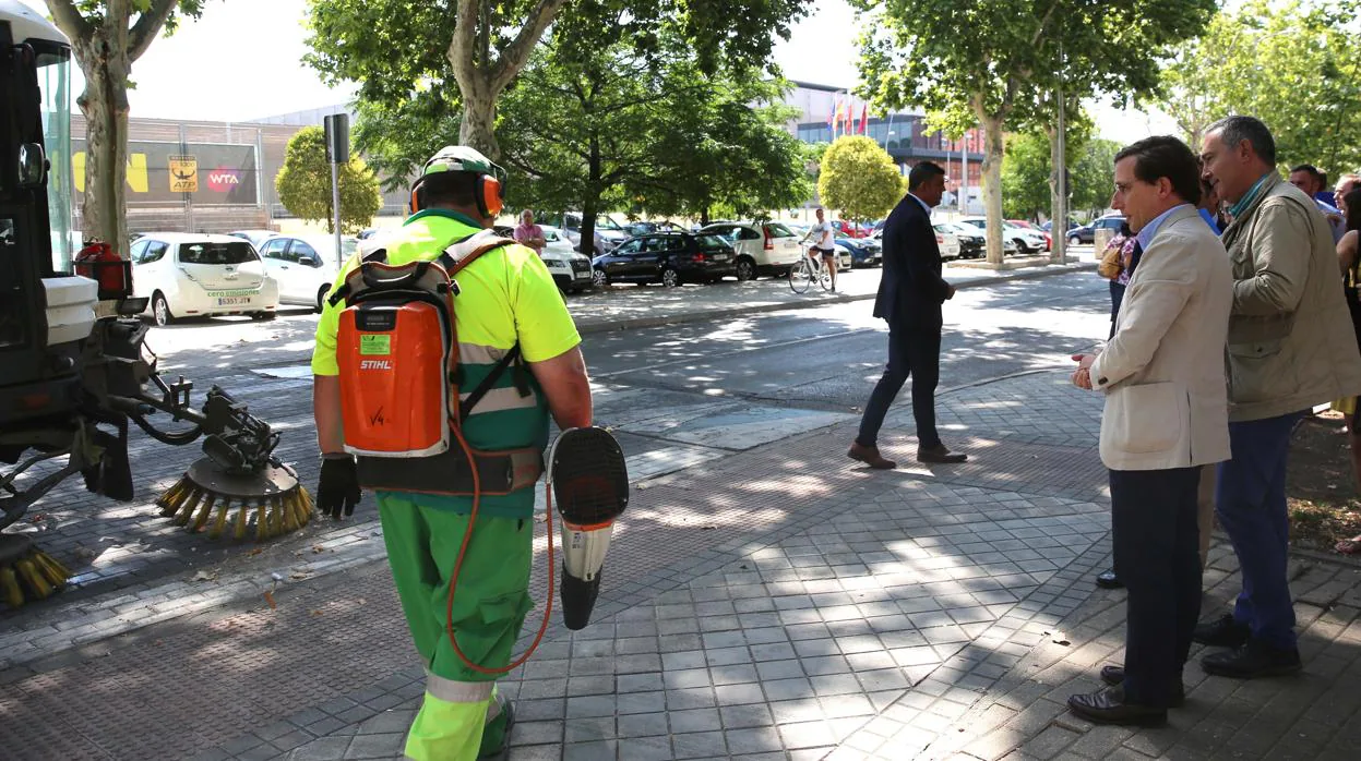 El alcalde de Madrid, José Luis Martínez-Almeida, observa cómo un operario de limpieza barre las hojas en el barrio de San Fermín