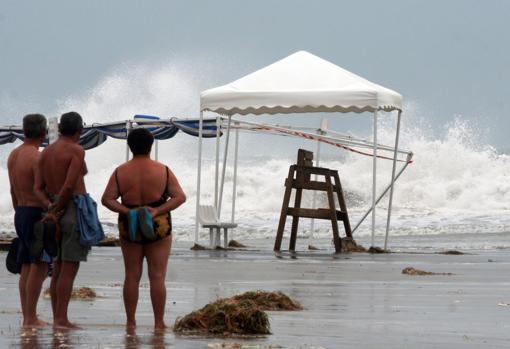 Imagen de archivo de tres personas en la playa durante un temporal en Alicante