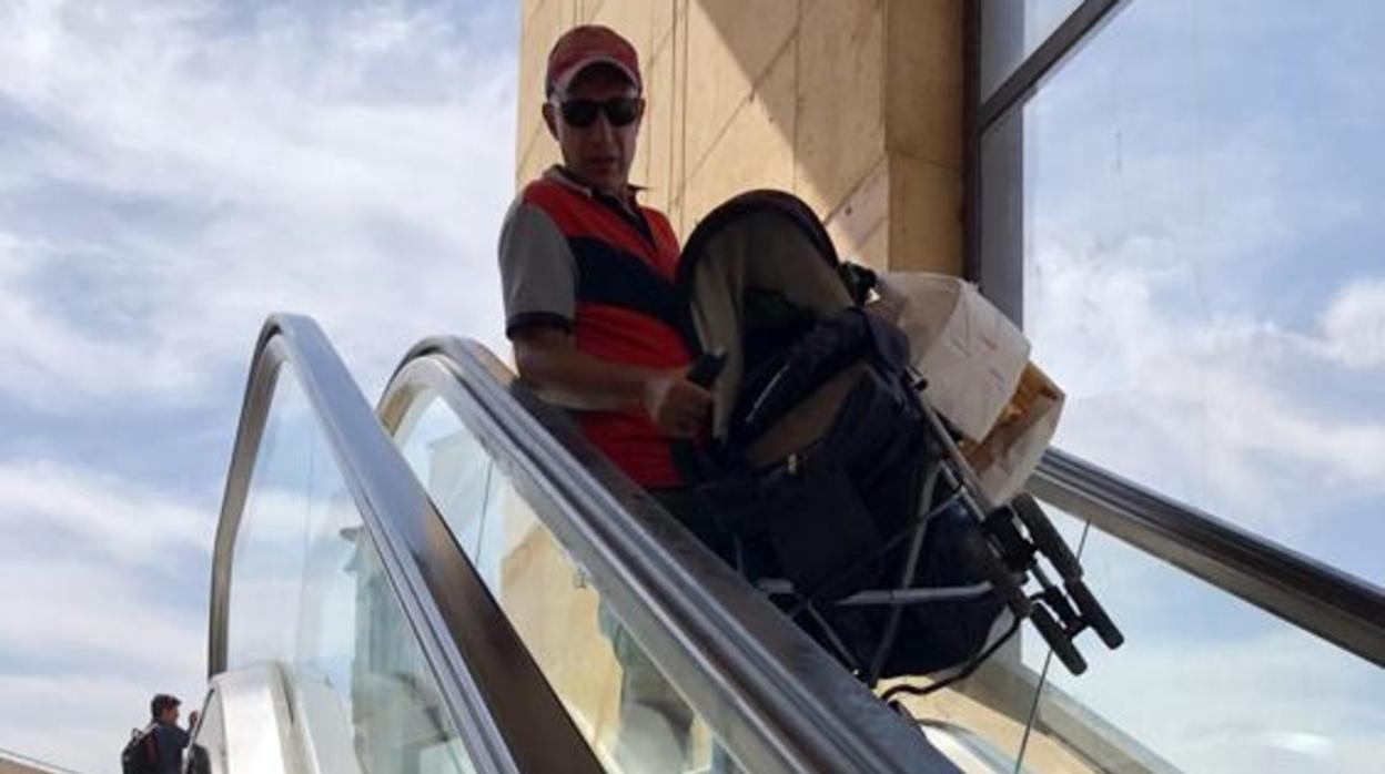 Un hombre, con el carro de un bebé, bajando el tramo de escaleras averiado