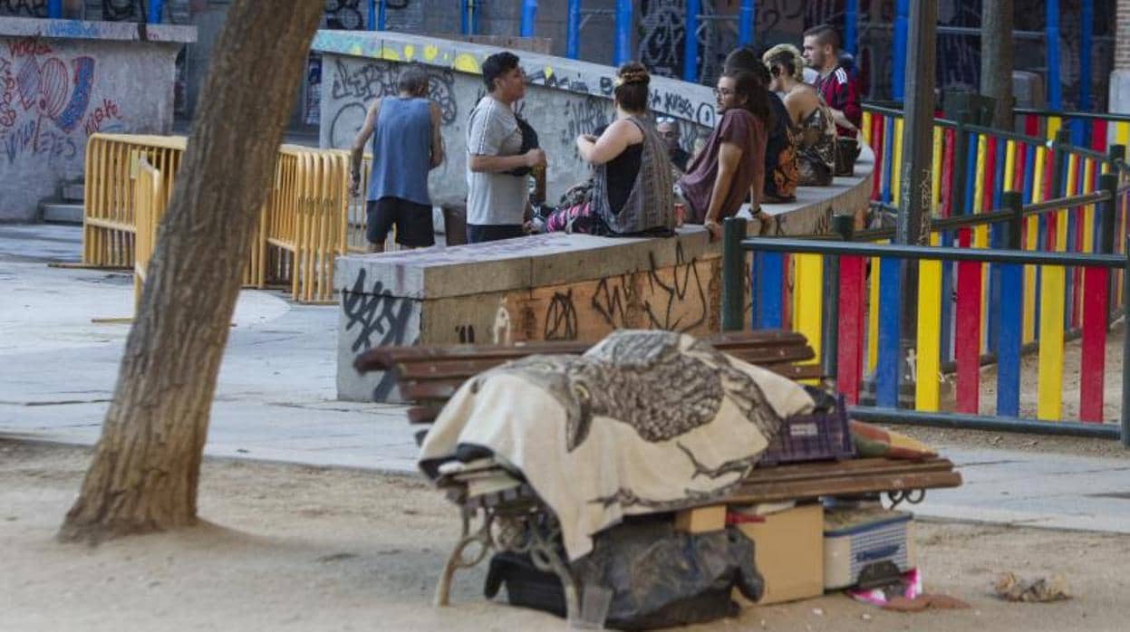 Un grupo de jóvenes bebe en plena calle delante de una persona sin hogar