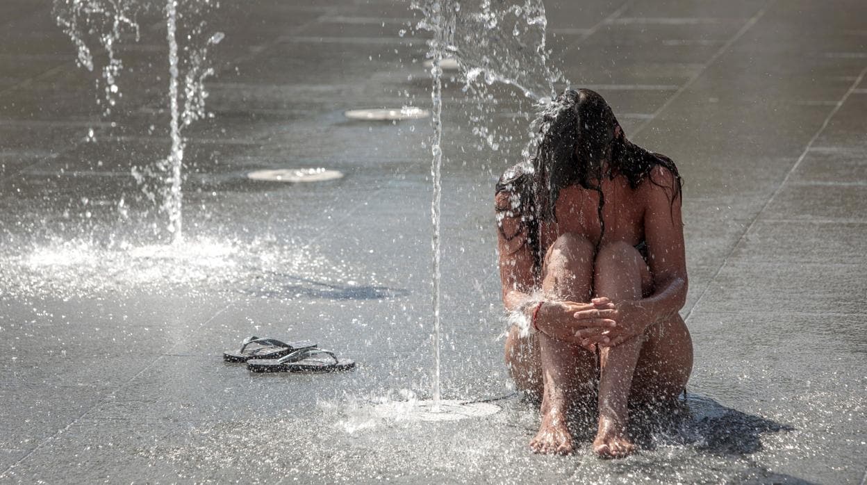 Una mujer se refresca en una fuente de Valencia