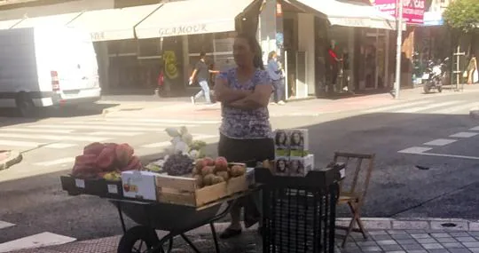 Una mujer vende fruta y tintes en la acera