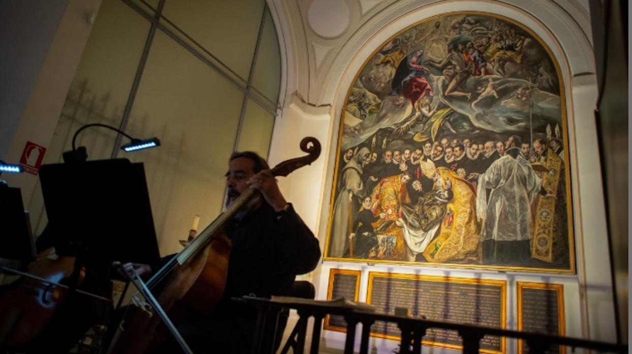 Uno de los músicos toca una pieza frente al cuadro del «Entierro del conde de Orgaz»