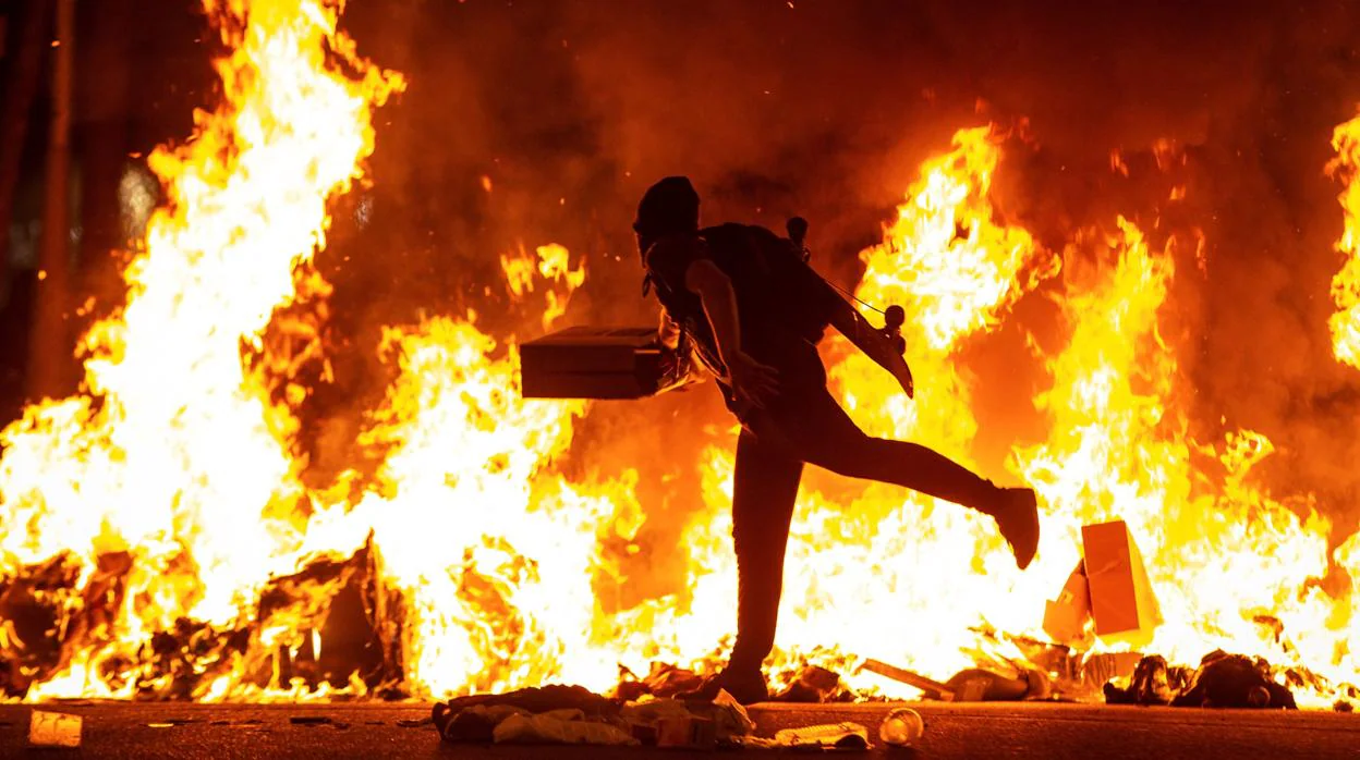 Un manifestante echa al fuego un cartón junto a la Delegación del Gobierno en Barcelona