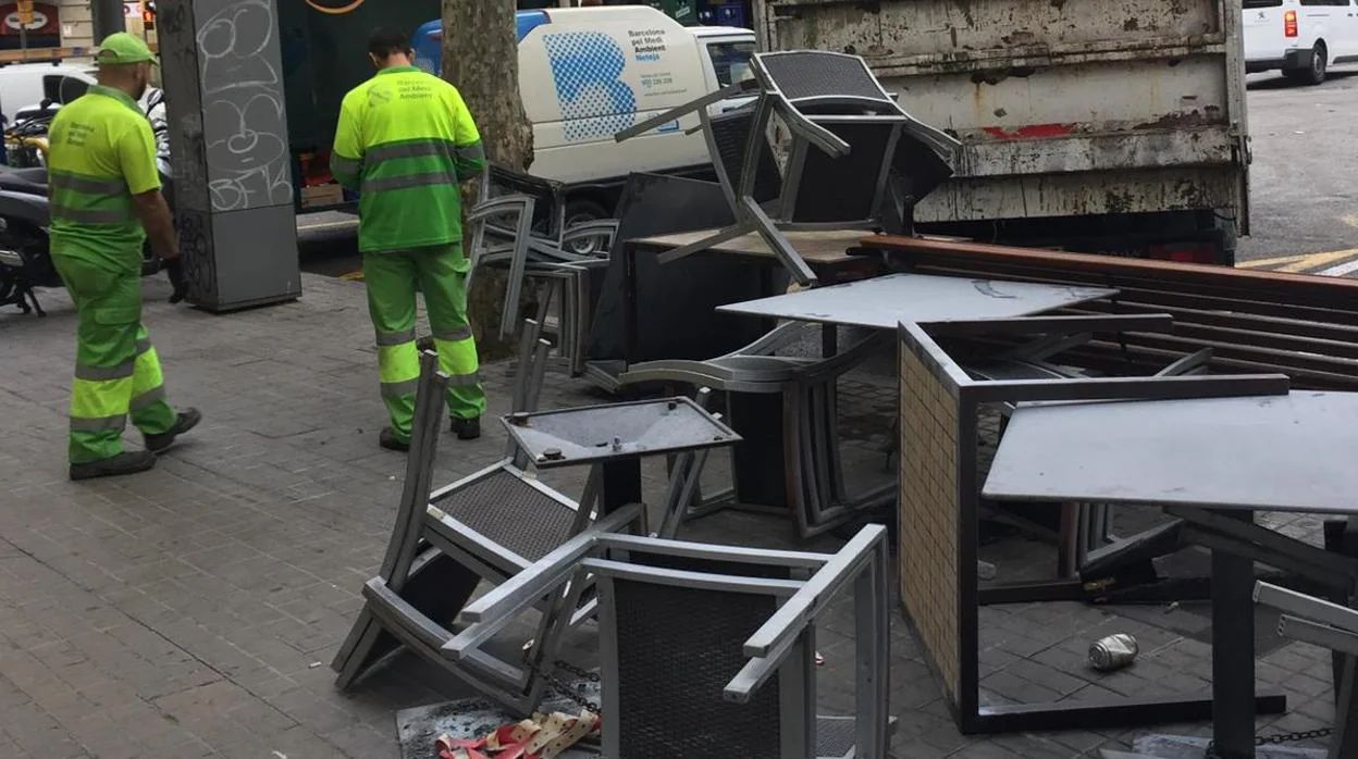 Empleados de limpieza recogen mobiliario urbano y de bares esta mañana en Barcelona