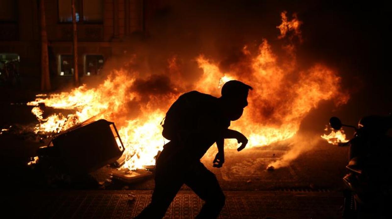 Un radical con las barricadas ardiendo durante los disturbios de Barcelona