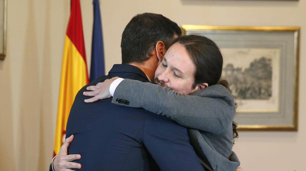 El presidente del Gobierno español en funciones, el socialista Pedro Sánchez, y el líder de Unidas Podemos, Pablo Iglesias, se abrazan en el Congreso de los Diputados tras firmar el acuerdo de Gobierno