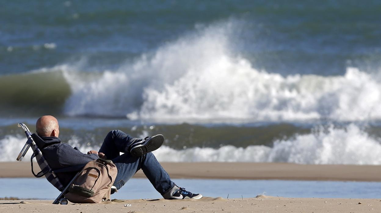 Imagen de archivo de un hombre abrigado contemplando el mar