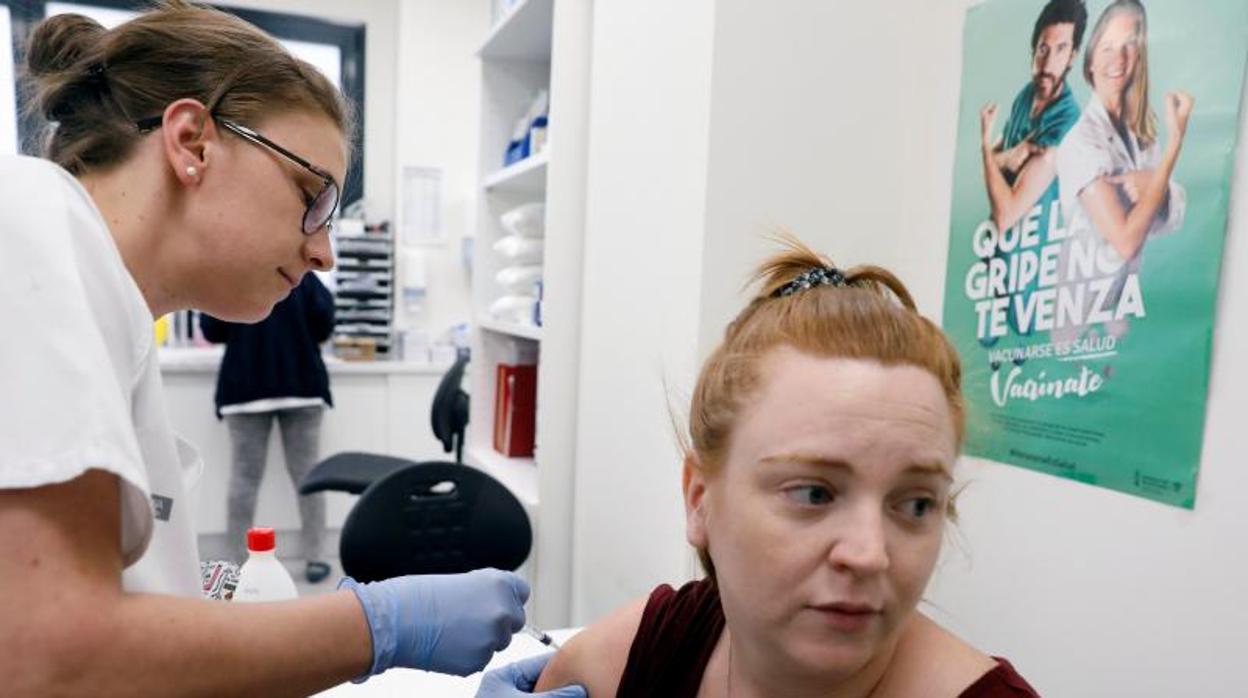 Una enfermera vacuna contra la gripe a una mujer en Valencia