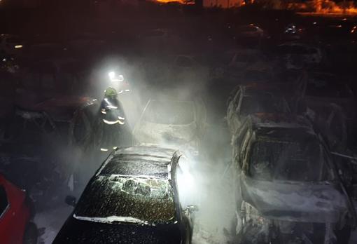 Efectivos de bomberos junto a varios vehículos destruidos por el fuego