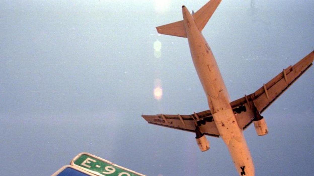 Una señal de tráfico junto al aeropuerto de Manises, con un avión sobrevolando la zona