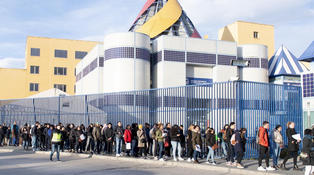 Una larga fila de personas hacen cola ante la Brigada Provincial de Extranjería, en Madrid