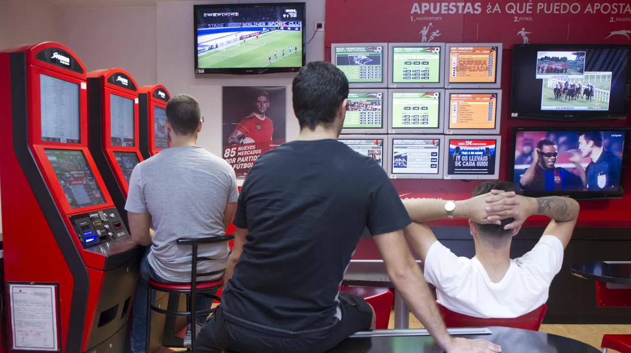 Varios jóvenes observan atentos las pantallas de una casa de apuestas en Madrid