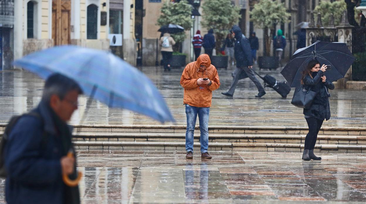 Varias personas se protegen de la lluvia en Valencia