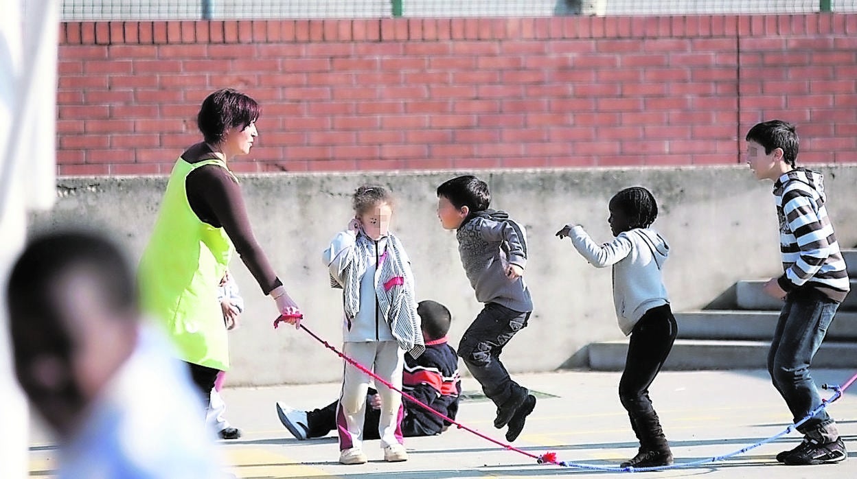 Una profesora juega con unos niños en el patio de un colegio