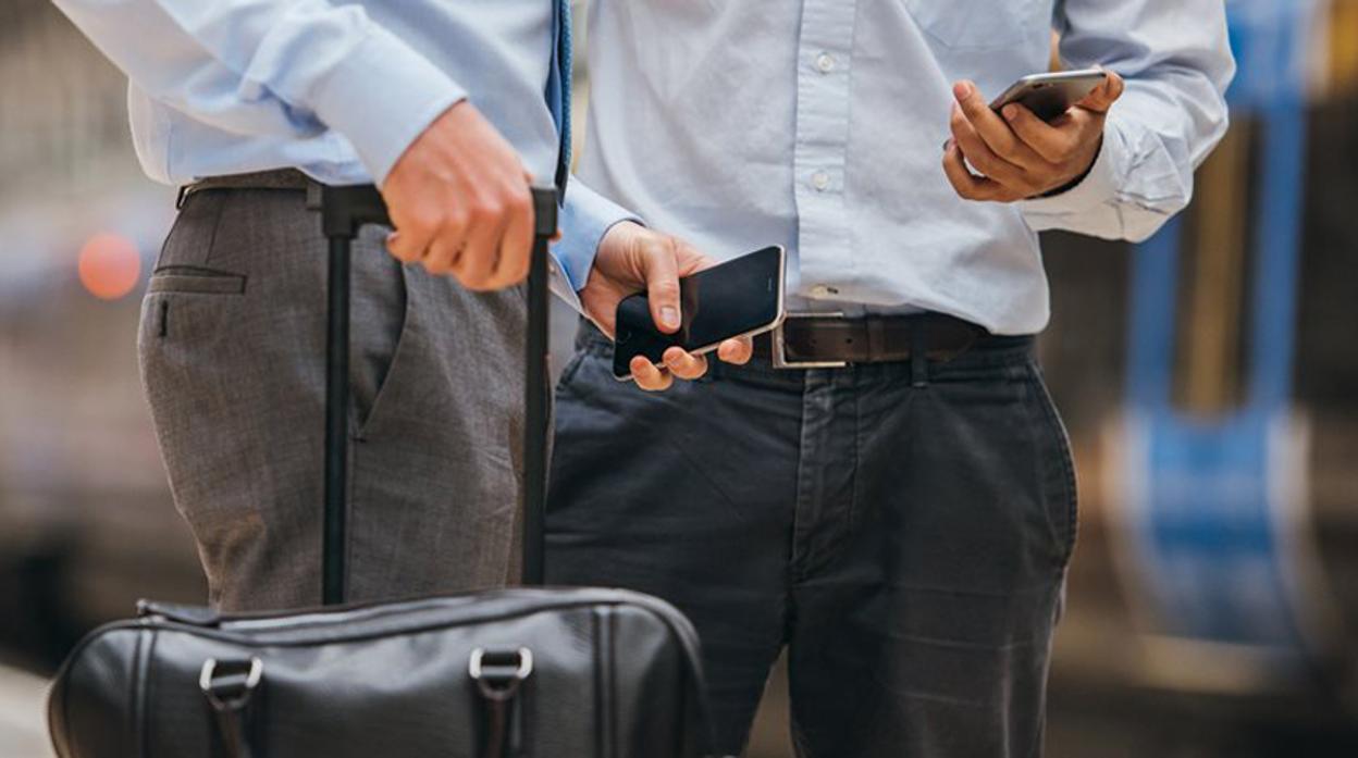 Dos ejecutivos utilizan sus teléfonos móviles