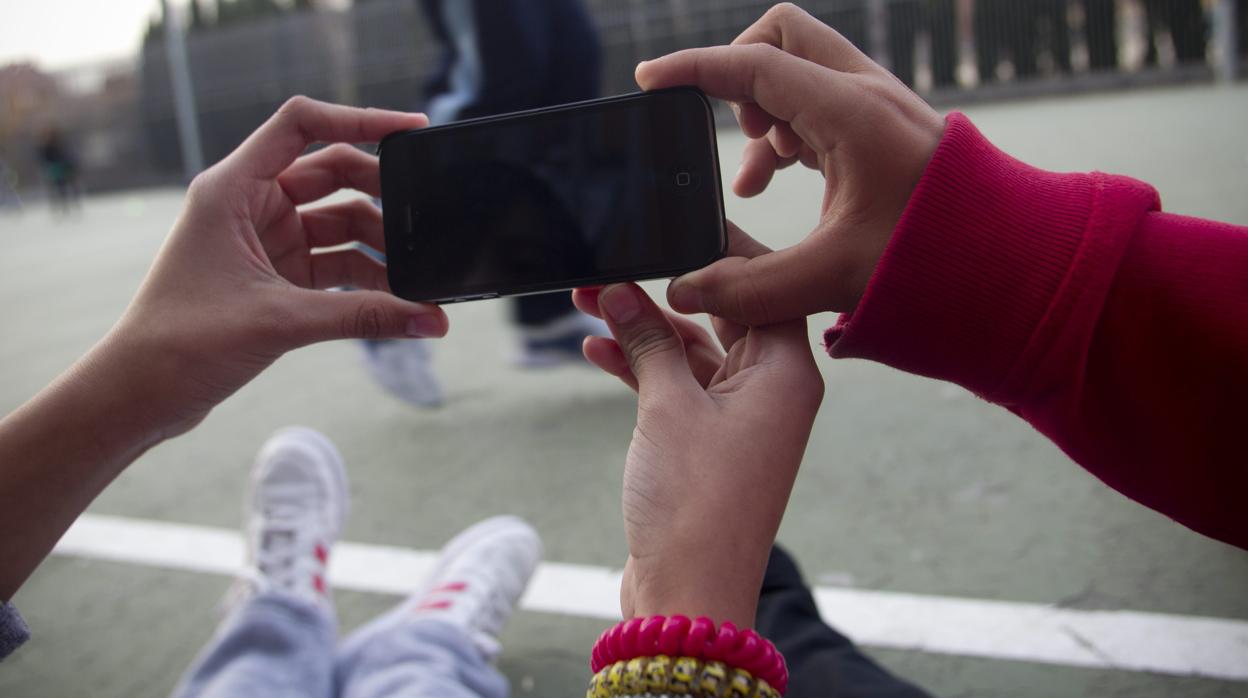 Imagen de archivo de varios adolescentes sujetando un teléfono móvil